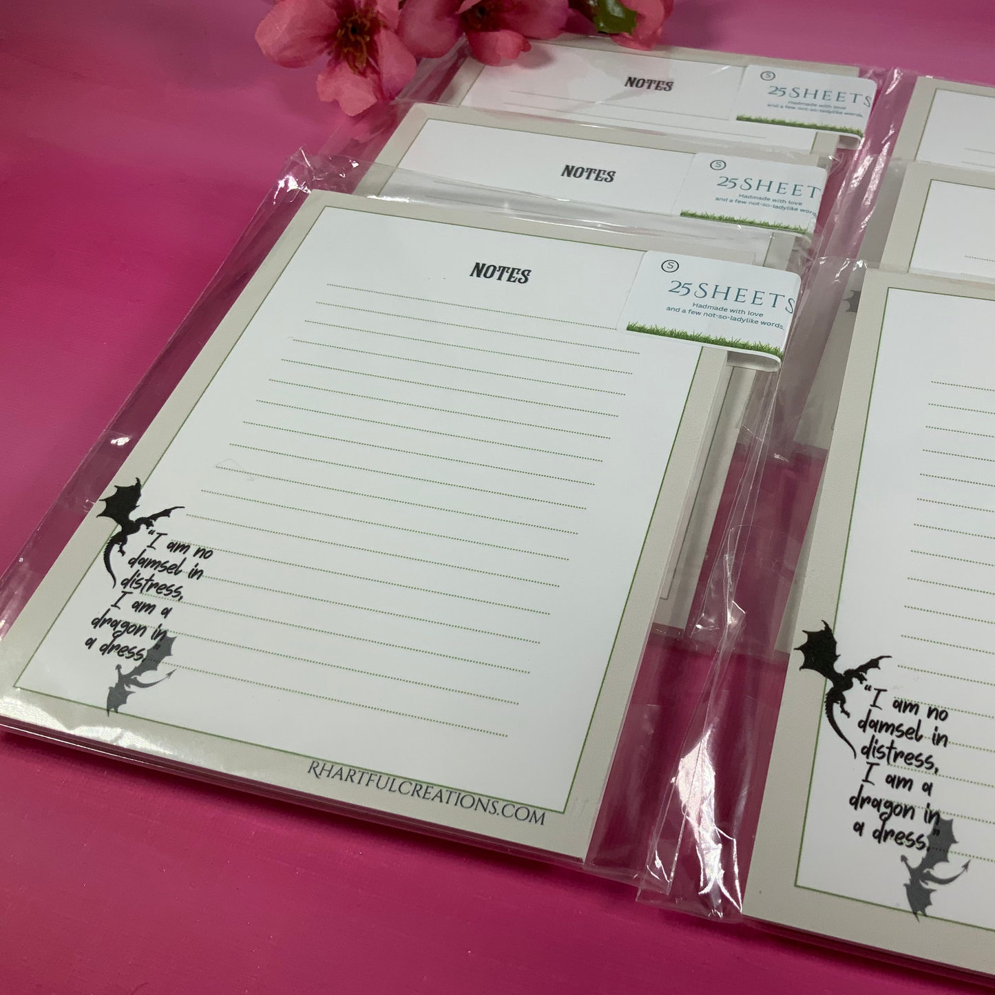 Note pads with writing prompts on a pink surface