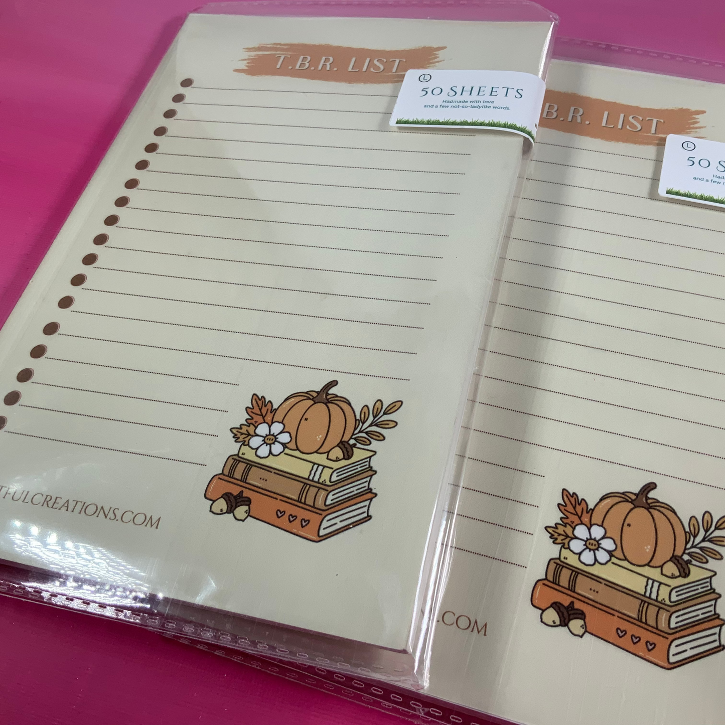 Two notepads with pumpkin design on a pink background