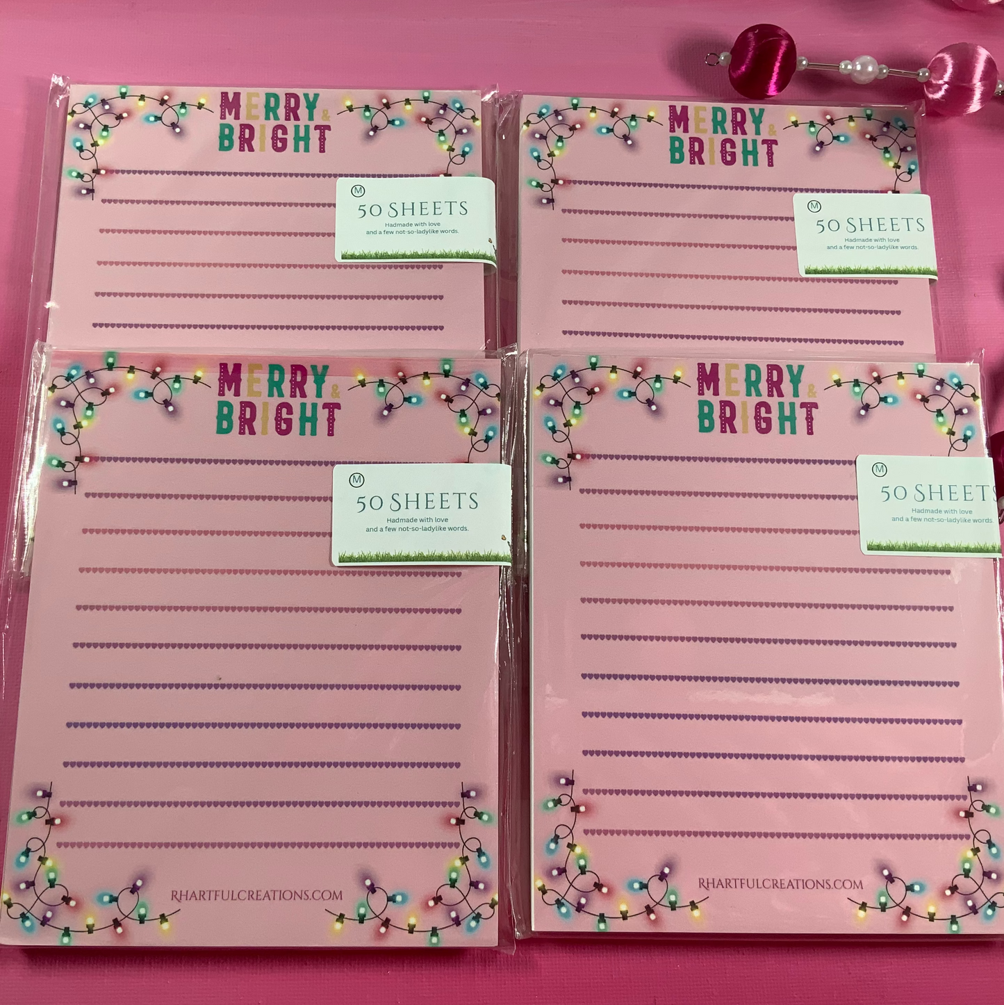 Set of four pink notepads with 'Merry Bright' text on a pink background