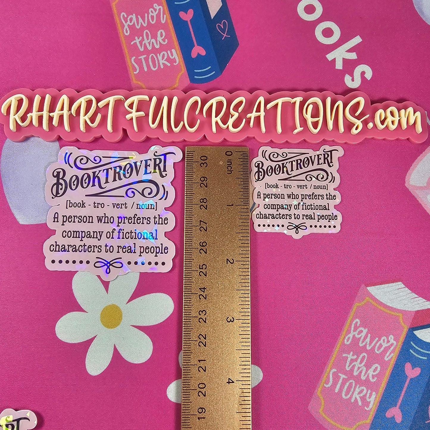 Pink fabric with book-themed designs and a ruler for scale on a pink background