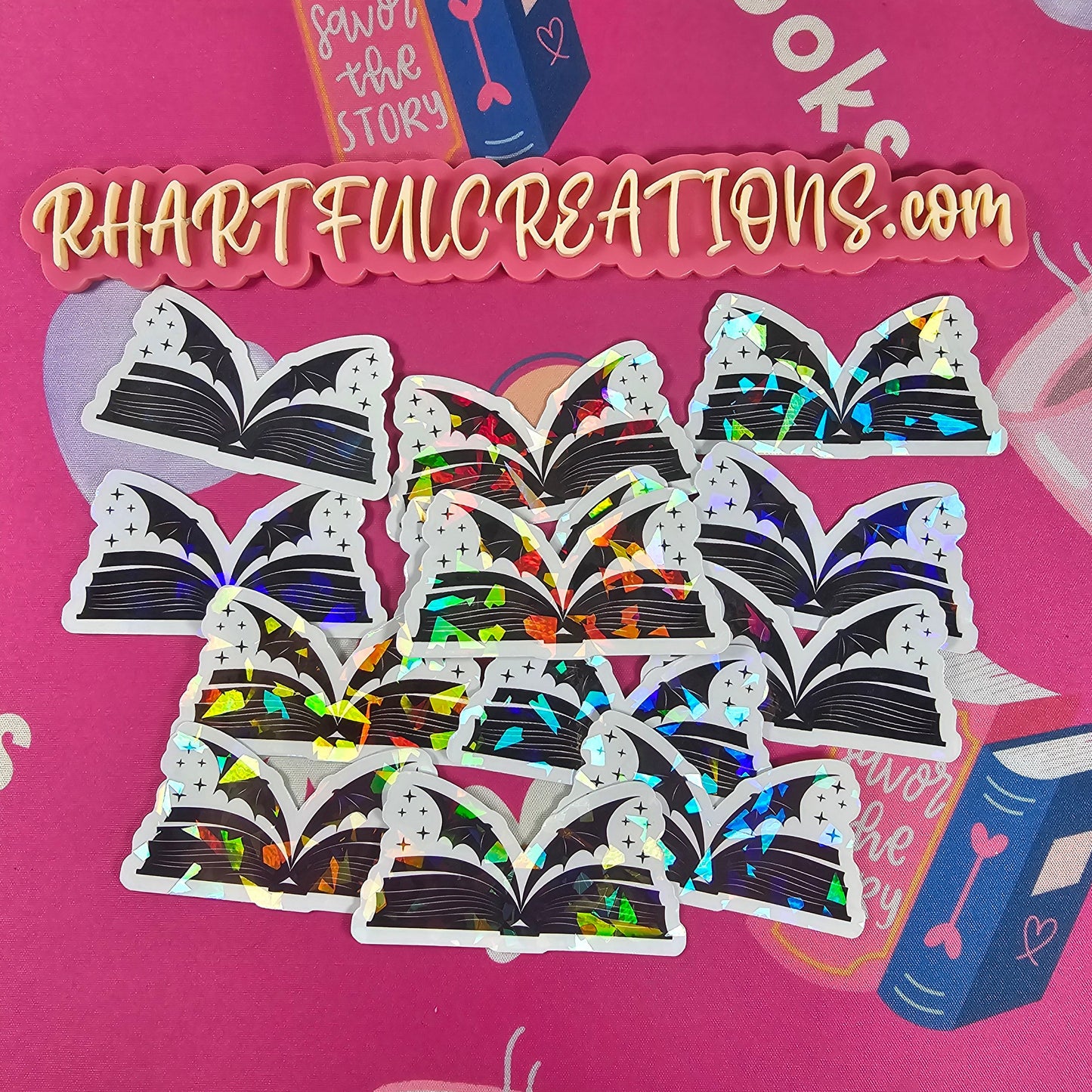 Holographic sticker shaped like an open book with magical wings, handmade by RH Artful Creations.