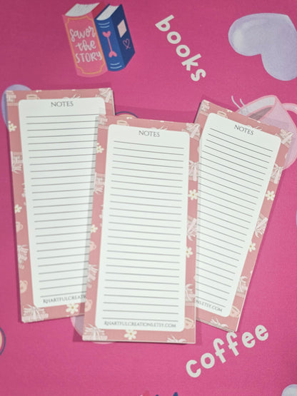 Set of three white notepads with pink borders on a pink surface with text and graphics.
