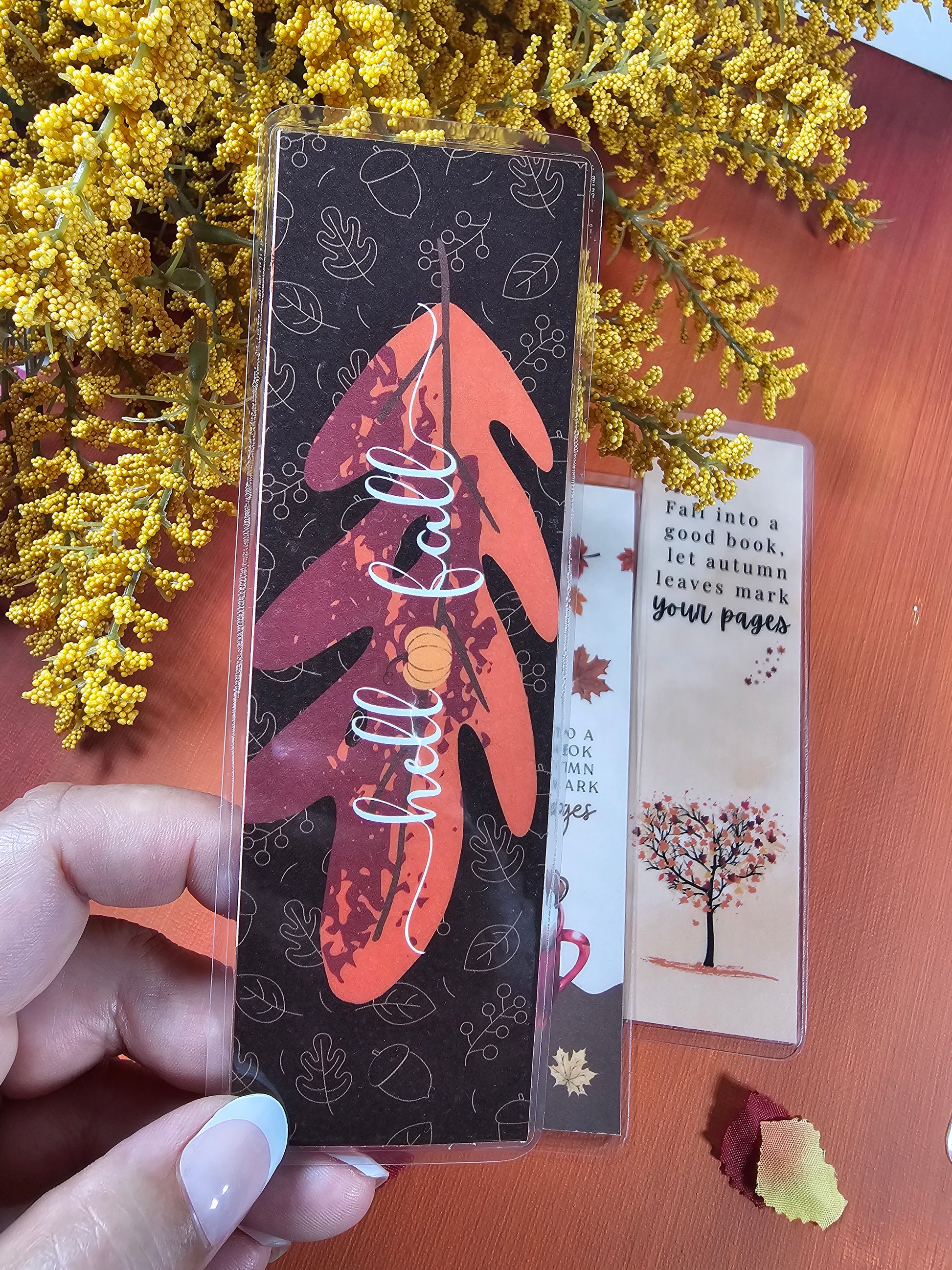 Hand holding a decorative box with 'Well Love' branding, surrounded by yellow flowers on a wooden surface.