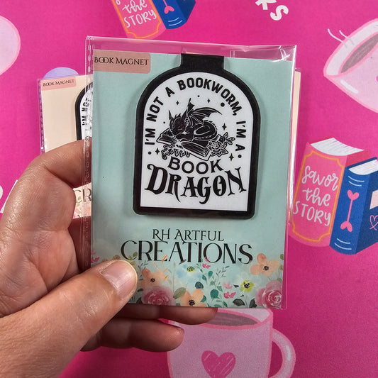 Hand holding a book with decorative cover against a pink background with books illustrations