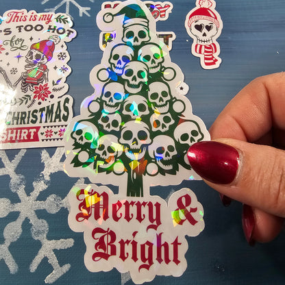 Hand holding a Christmas-themed sticker with 'Merry & Bright' text on a blue background with snowflakes.