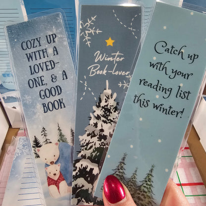 Hand holding a set of winter-themed bookmarks with text and snowflake designs.