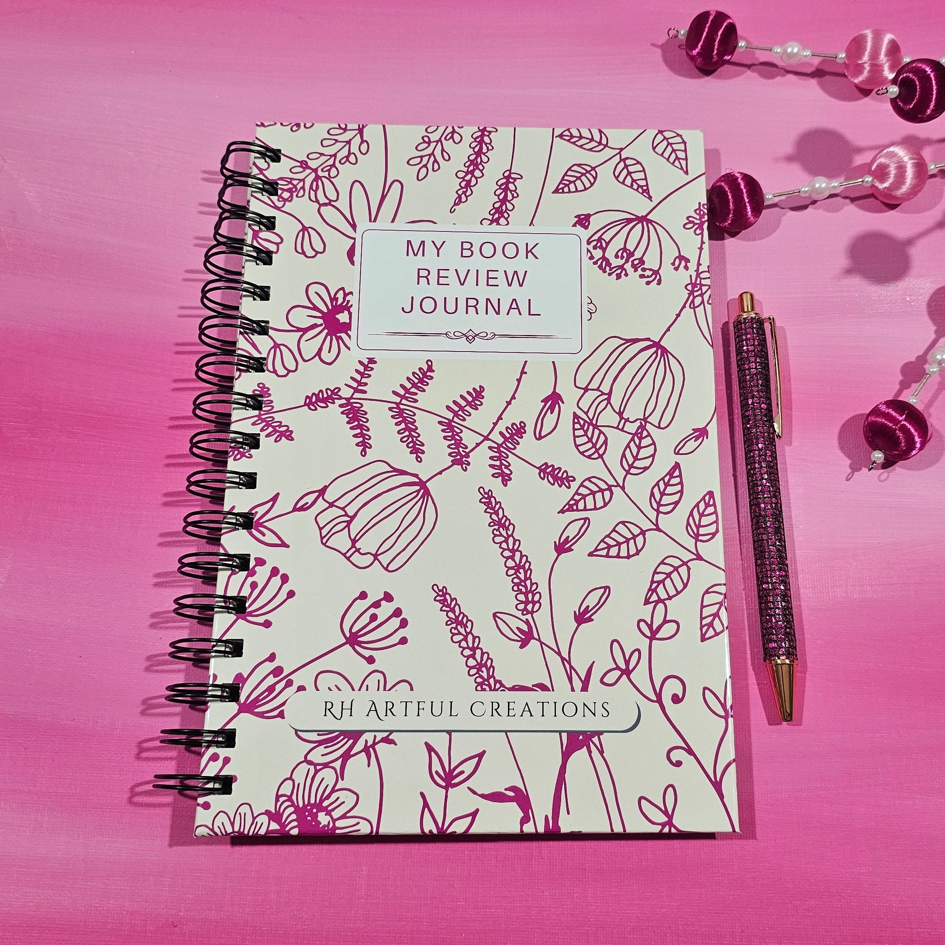 Valentine-themed spiral book review journal with magenta floral cover by RH Artful Creations on a pink background.