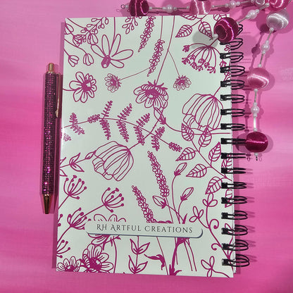 Notebook with floral design and pen on a pink background