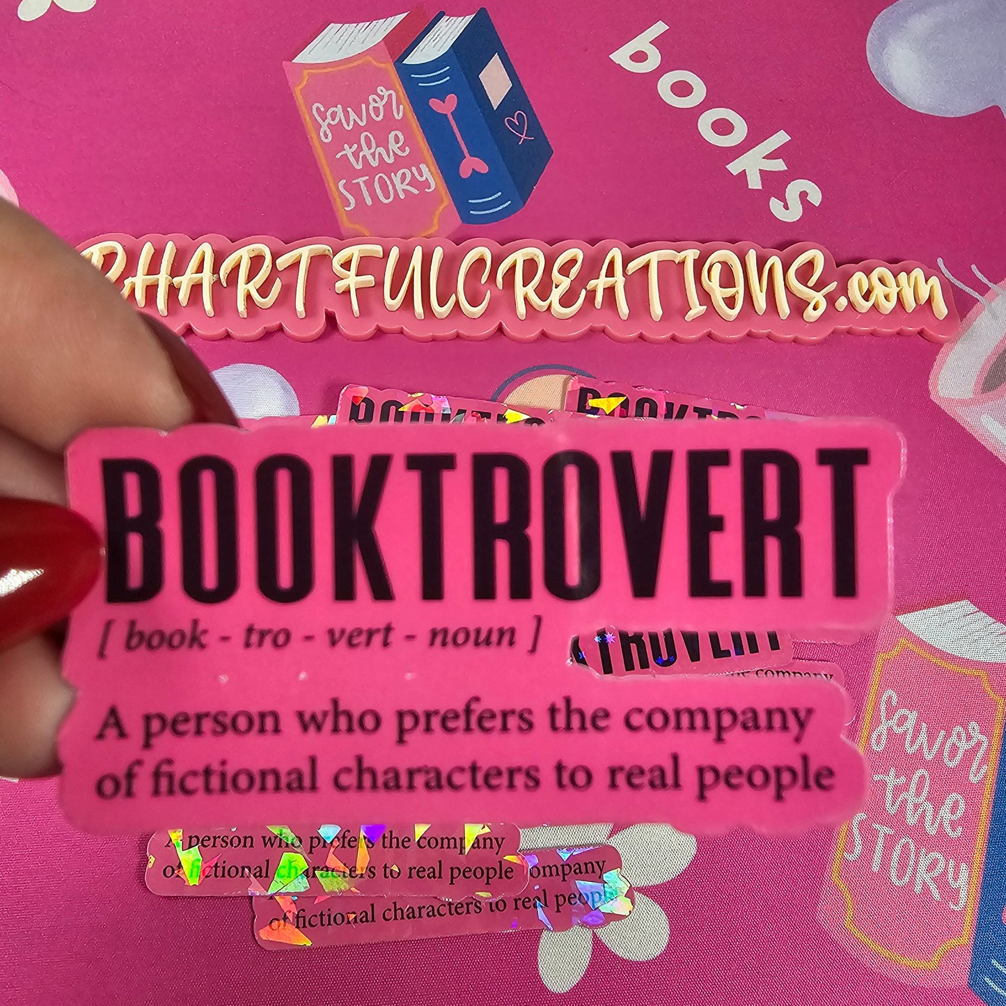 Pink bookmark with 'BOOKTROVERT' text held against a pink background with cartoon characters.