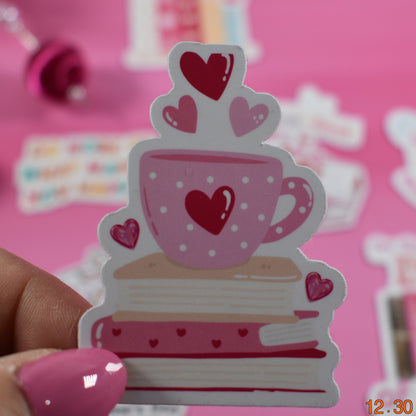 Sticker of a pink teacup with hearts held by a hand on a pink background
