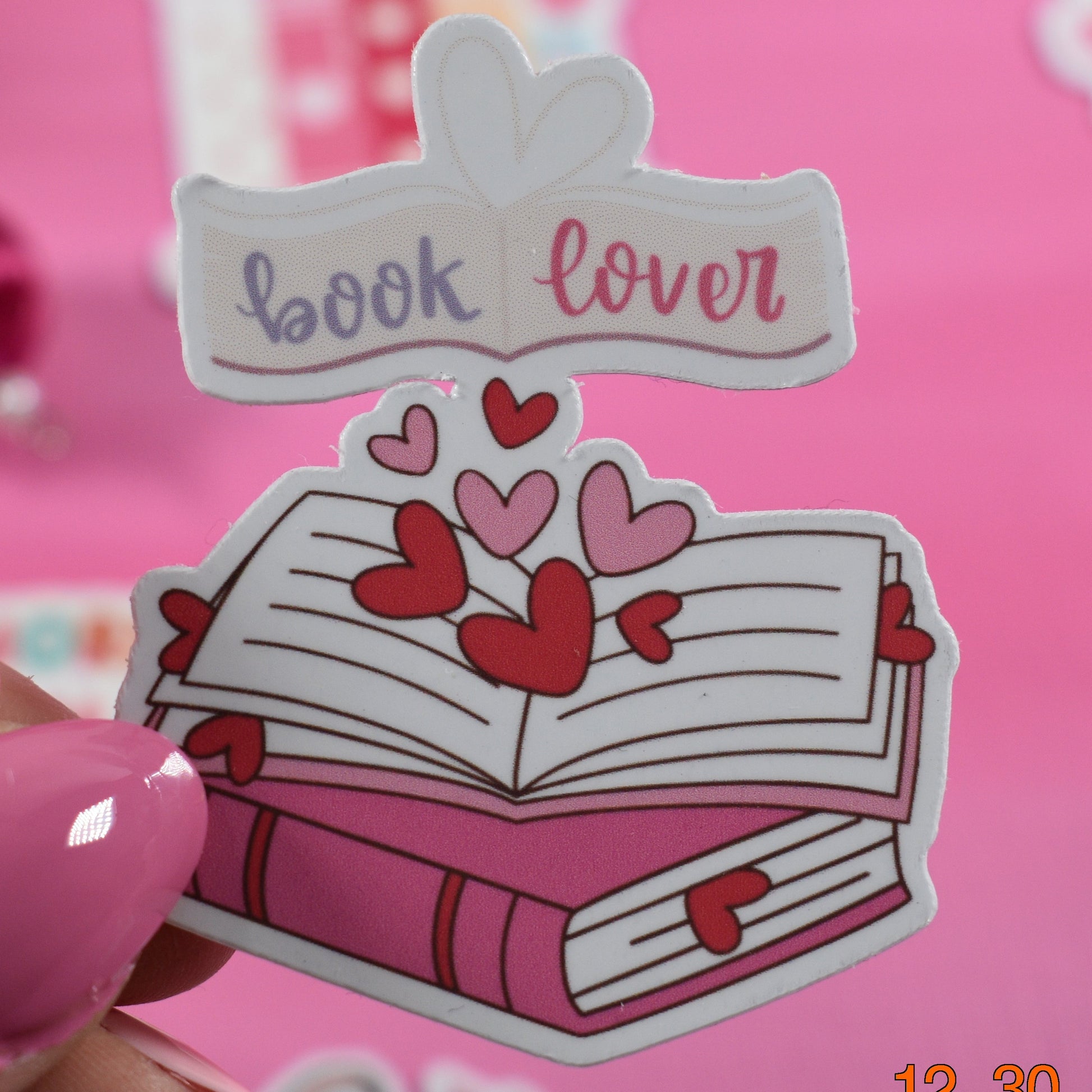 Sticker with 'book lover' text and hearts on a pink background