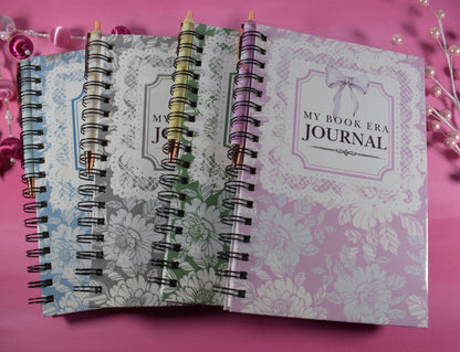 Two spiral-bound journals on a pink background with decorative items.