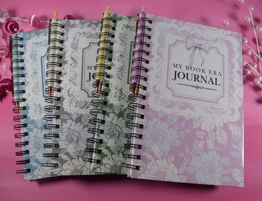 Two spiral-bound journals on a pink background with decorative items.