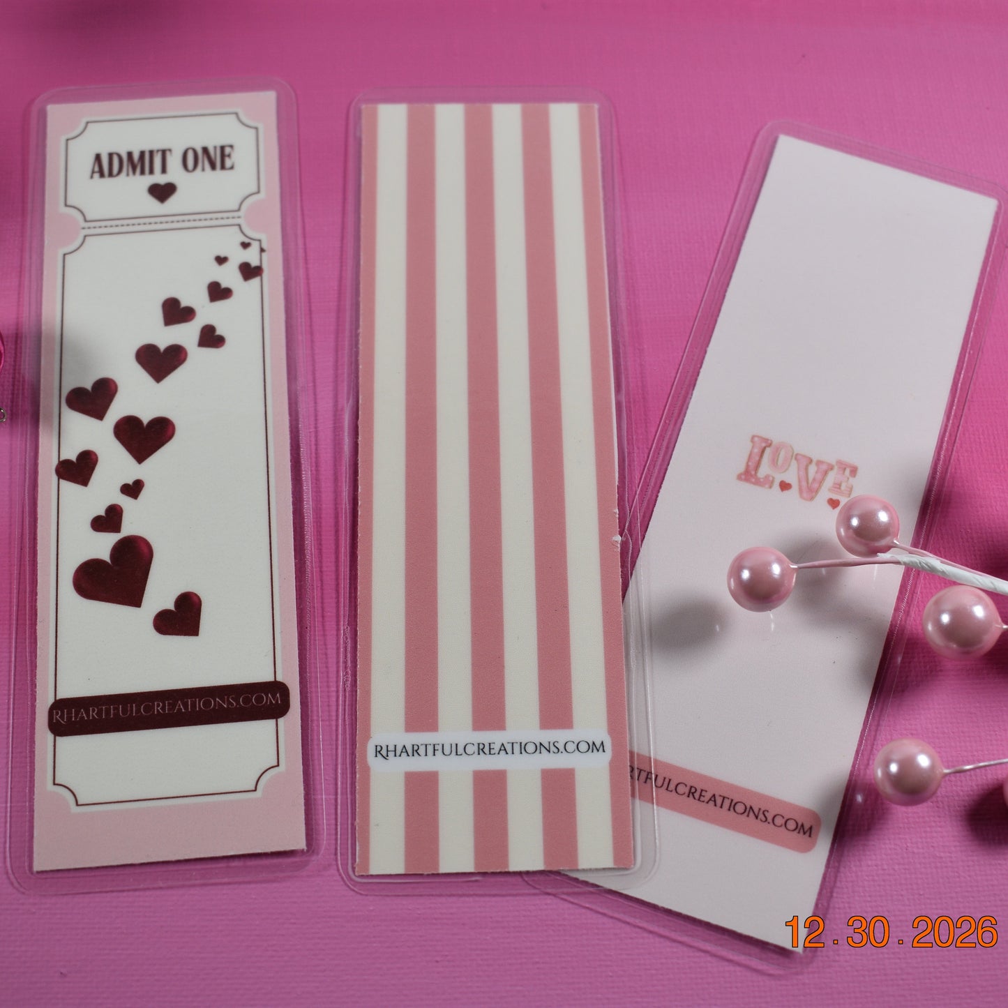 Three decorative bookmarks with heart designs on a pink background