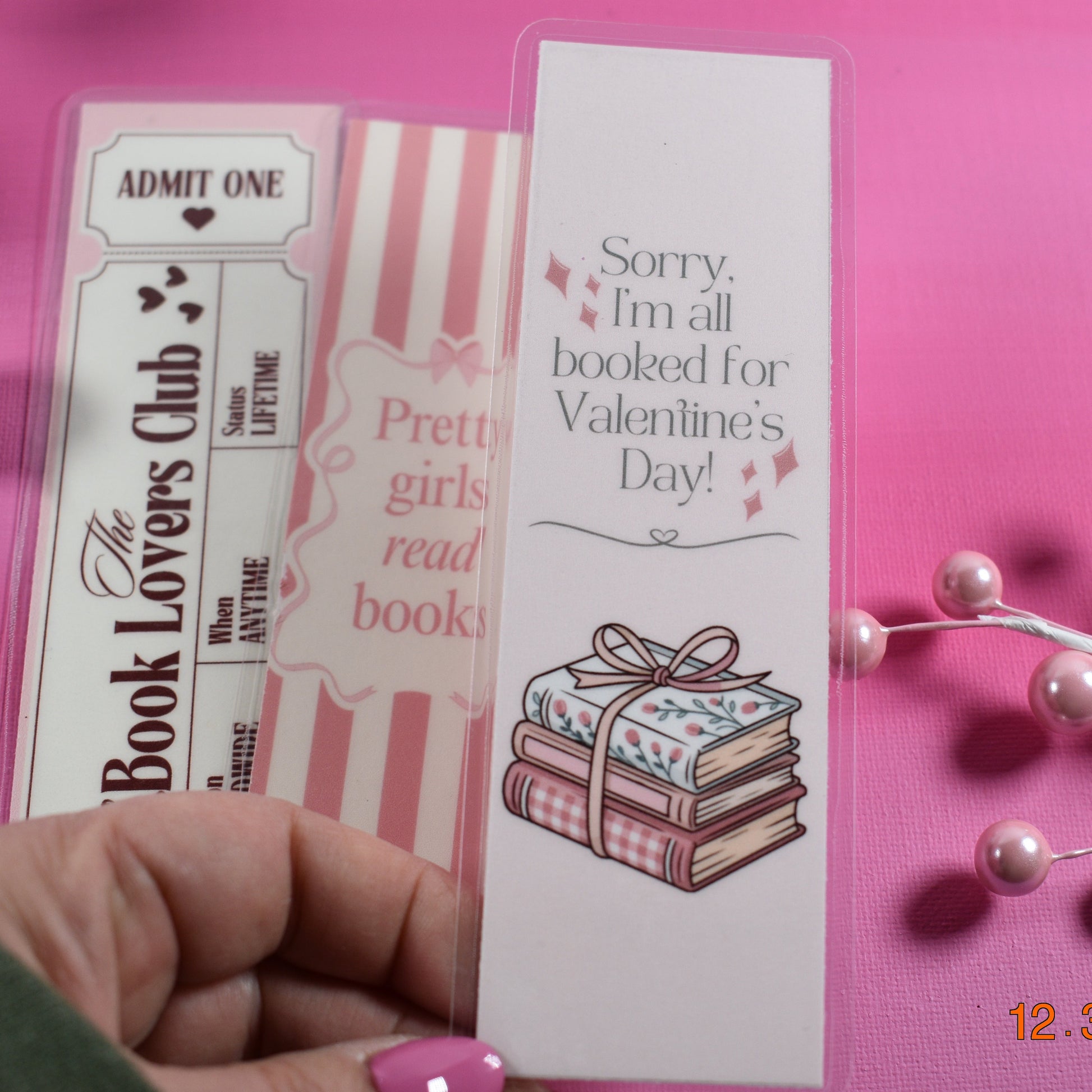 Valentine's Day-themed bookmarks with decorative elements on a pink background.
