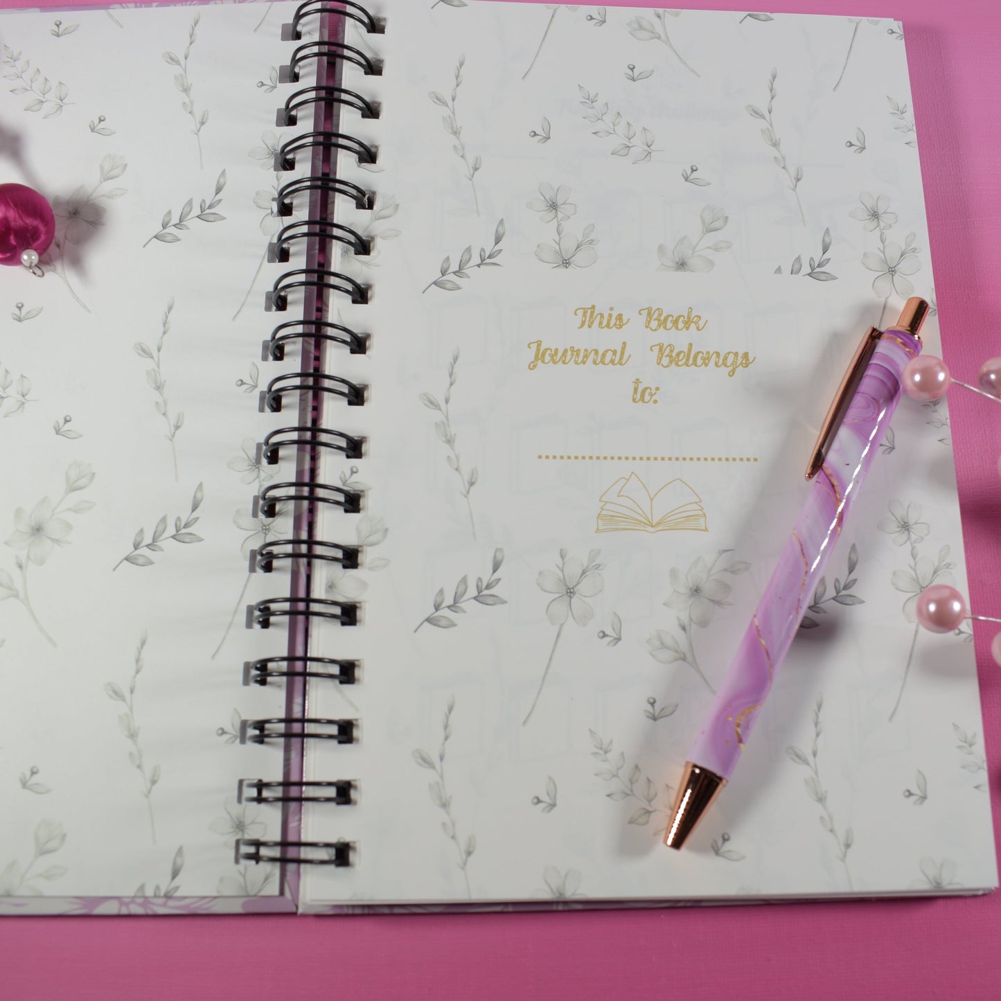 Journal with a pen on a pink surface