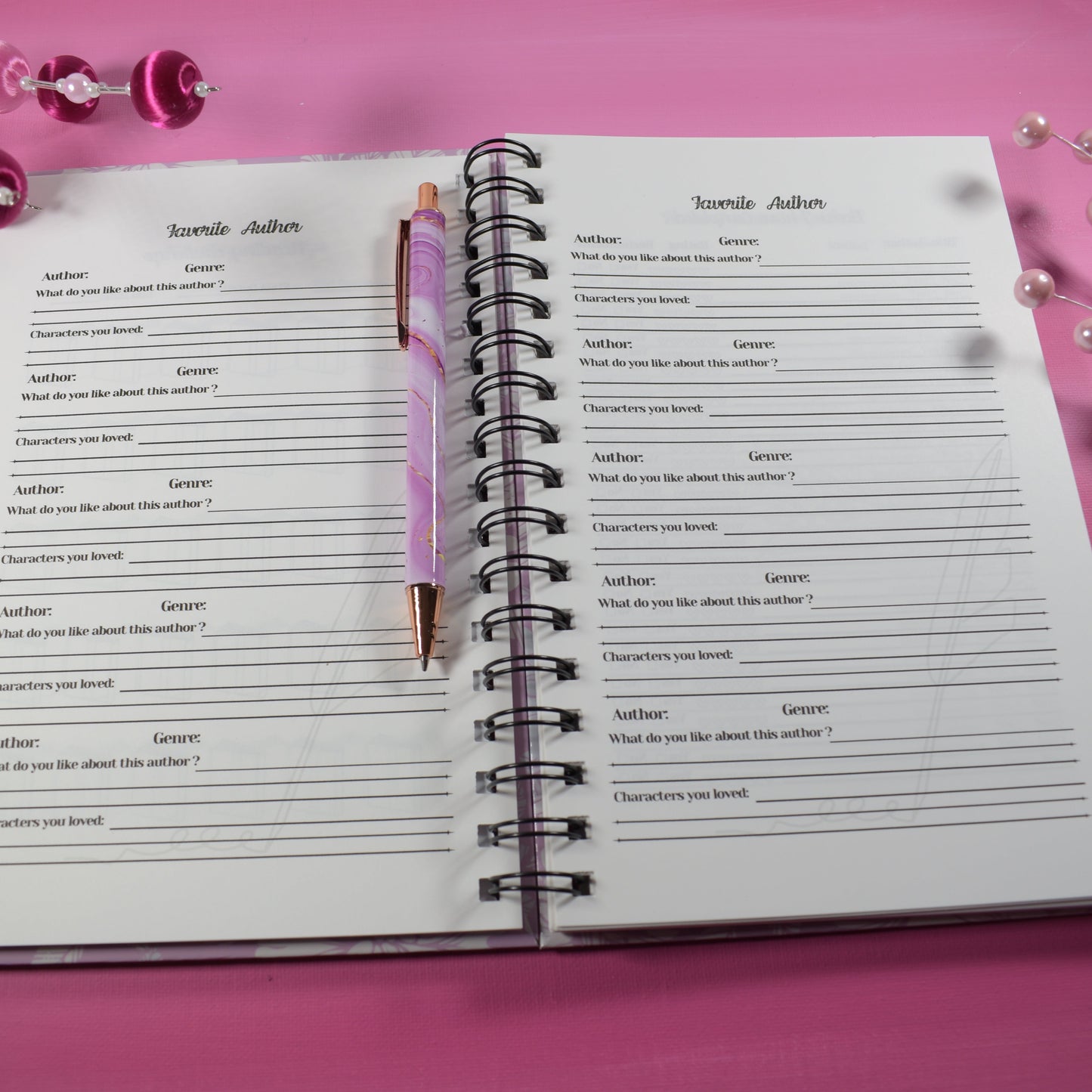 Open notebook with a pen on a pink background