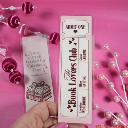 Hand holding a 'Book Lovers Club' card with decorative elements on a pink background