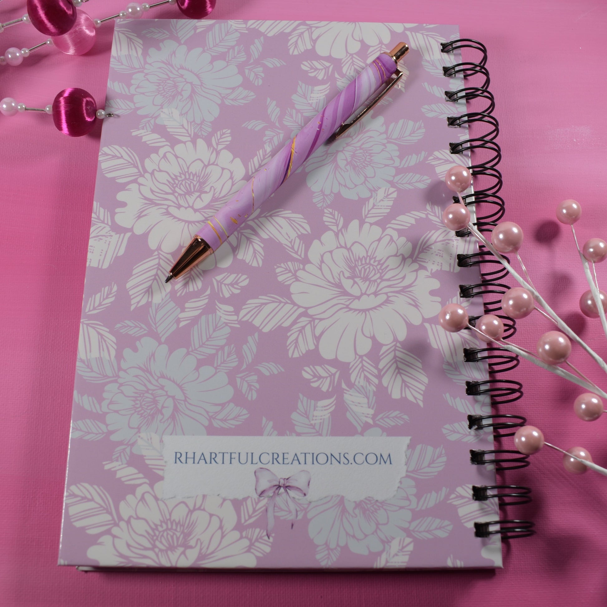 Floral notebook with a pen on a pink background