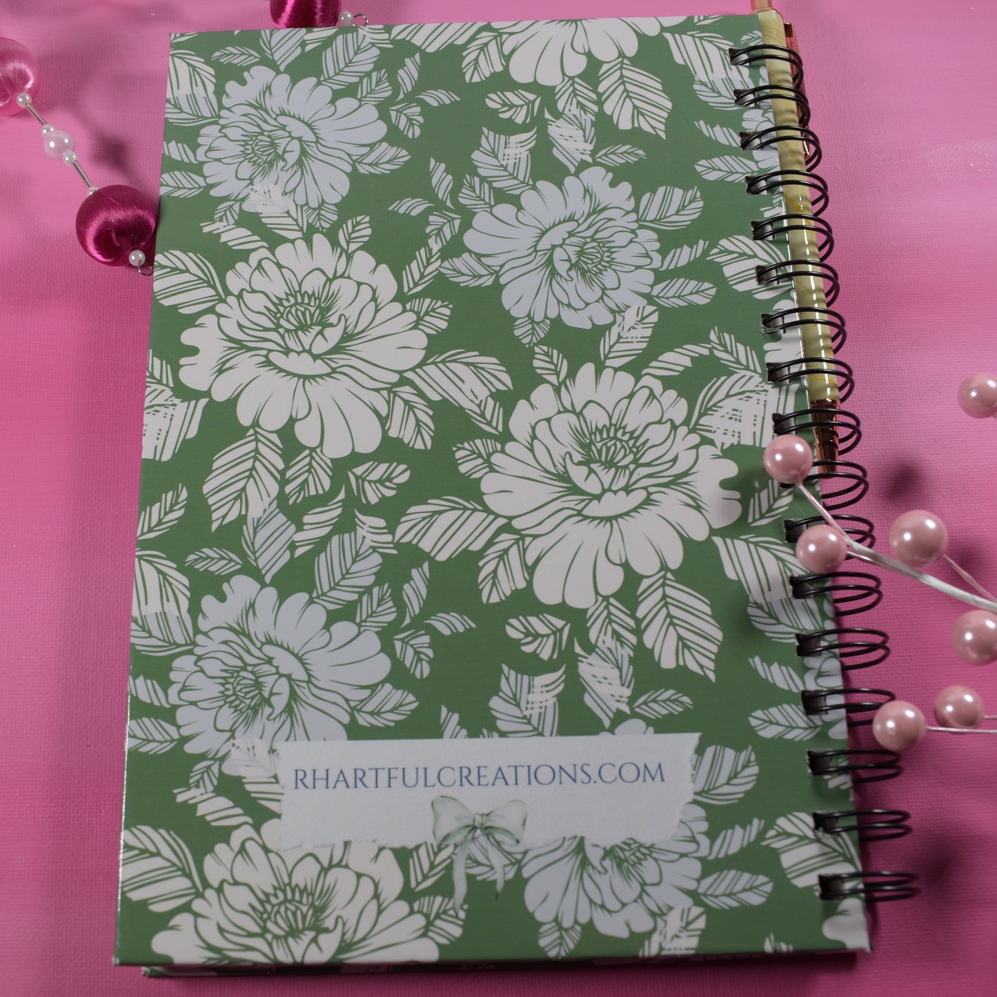 Green notebook with floral pattern on a pink background