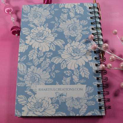 Floral notebook on a pink background with decorative elements
