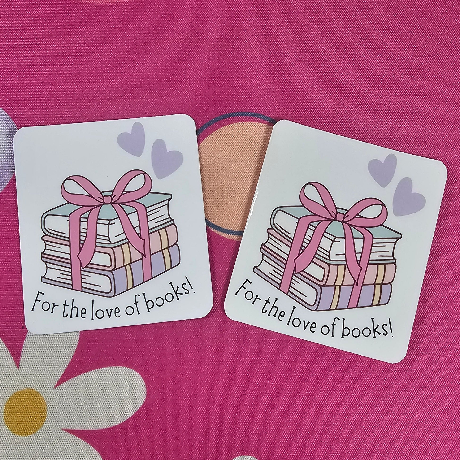 Two decorative stickers with book illustrations and text on a pink background with flowers.