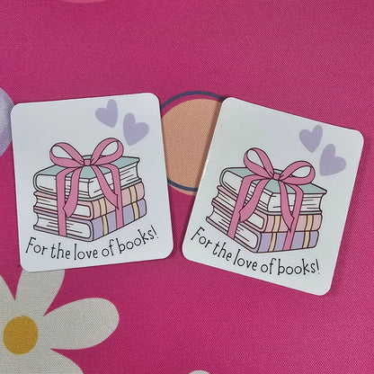 Two decorative stickers with book illustrations and text on a pink background with flowers.