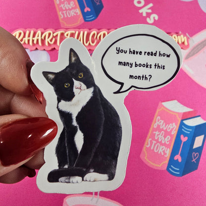 Sticker of a black-and-white cat with speech bubble saying “You have read how many books this month?”  handmade book lover sticker