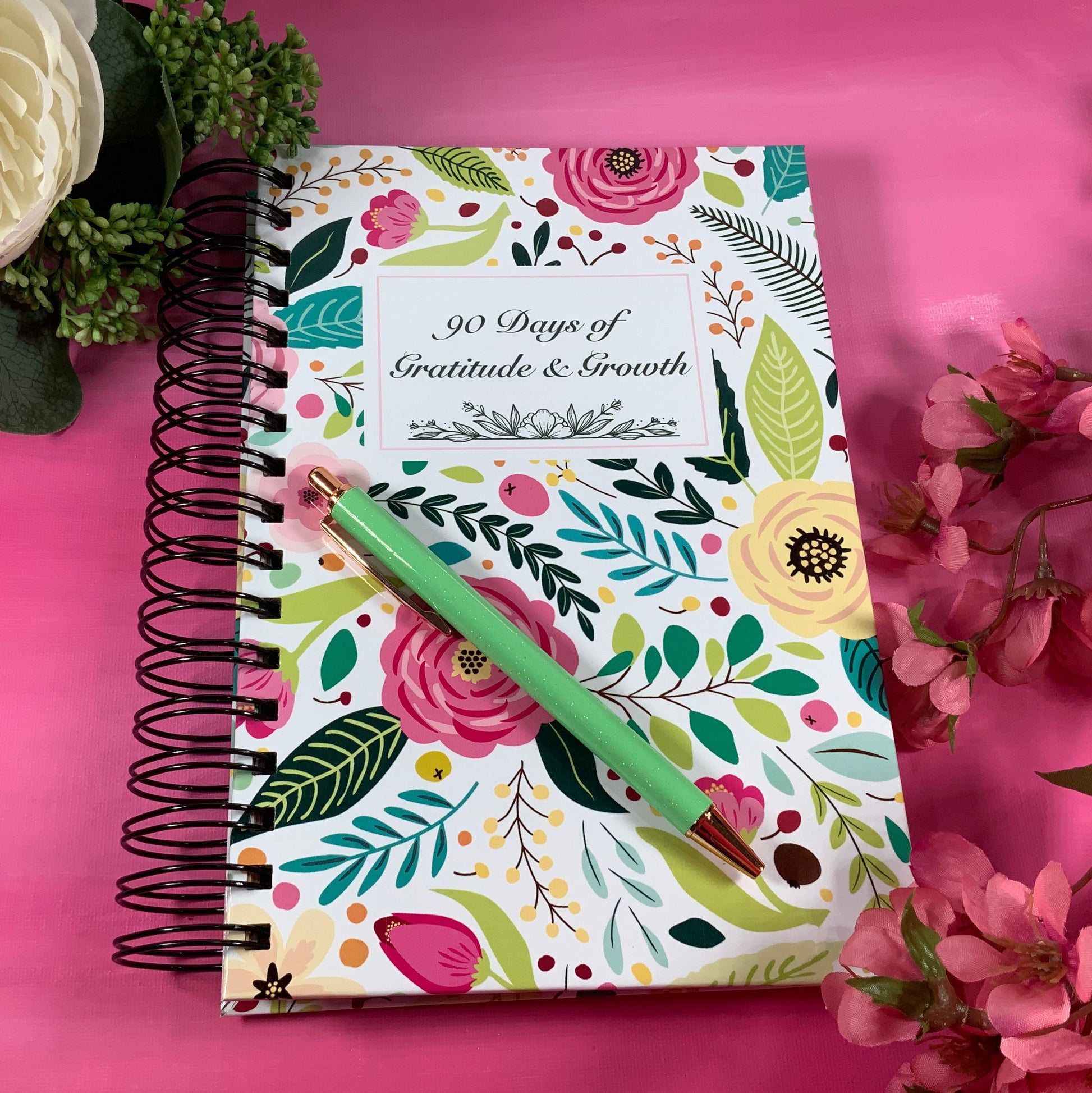 Floral notebook with a pen on a pink background