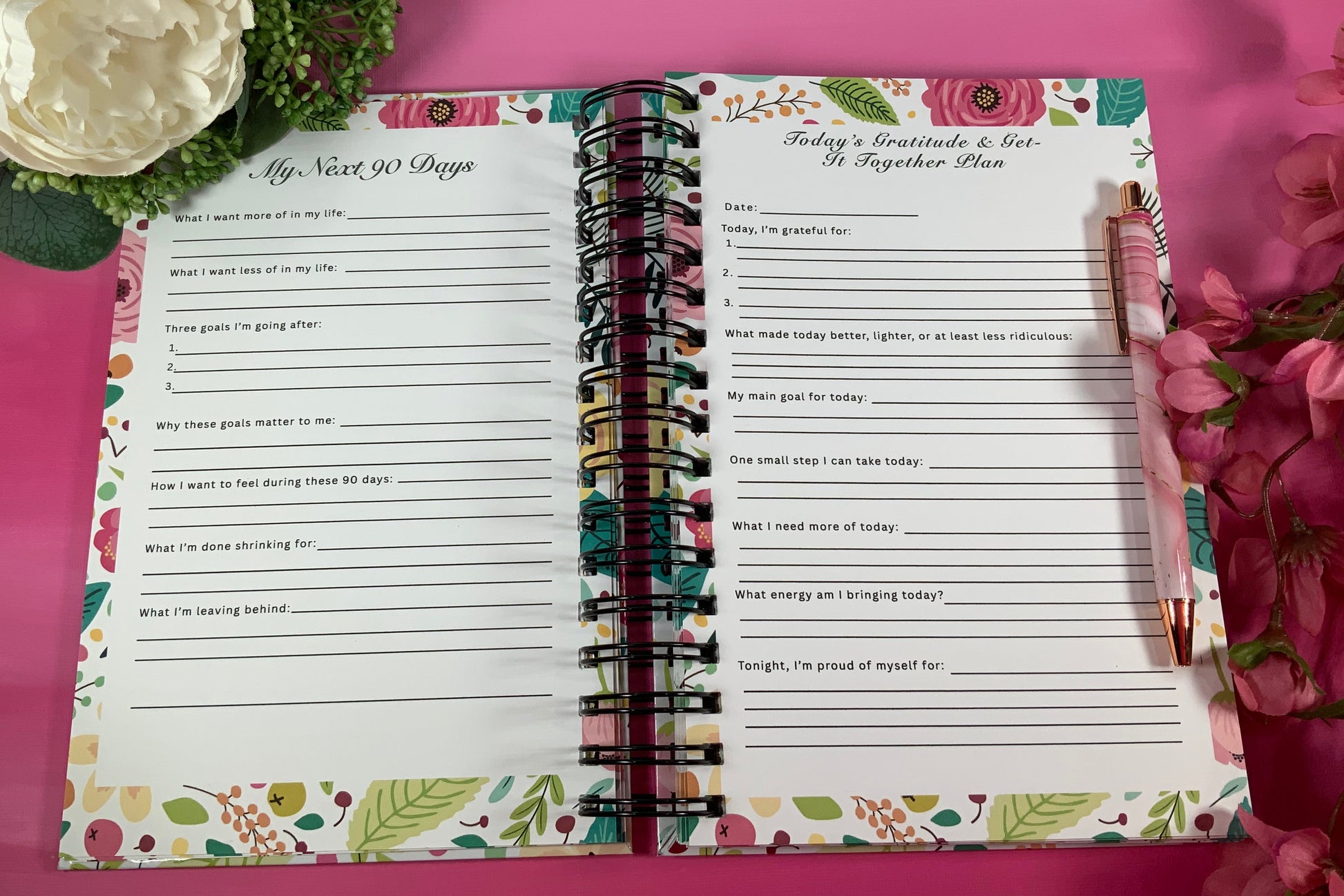 Open planner with printed pages on a pink background with flowers