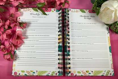 Open planner with floral design on a pink background