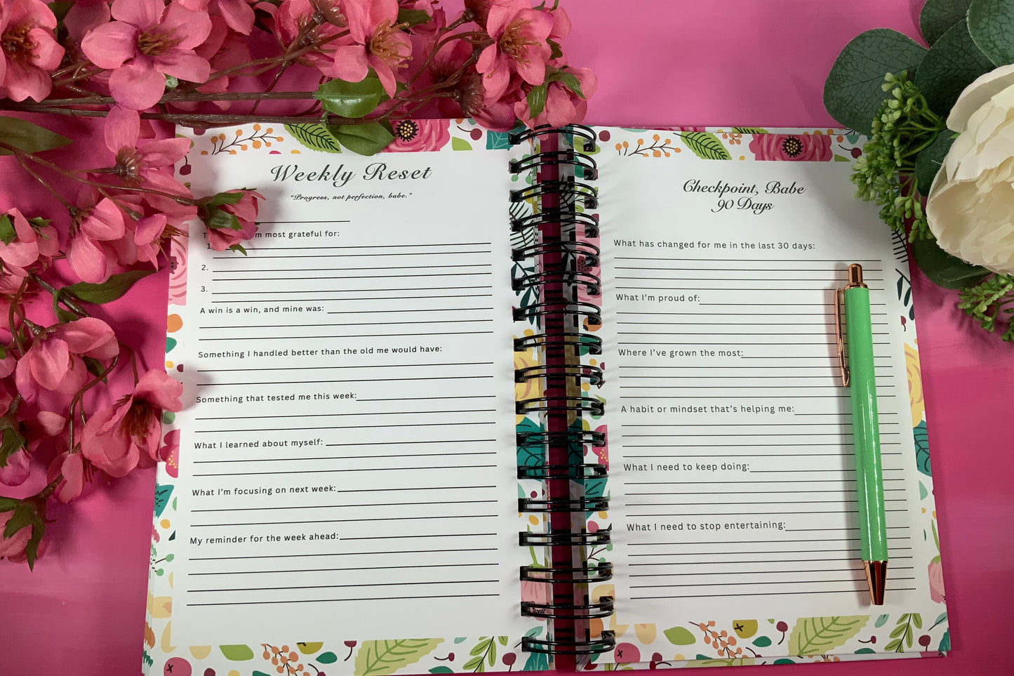 Open planner with weekly反省页面 on a pink background with flowers