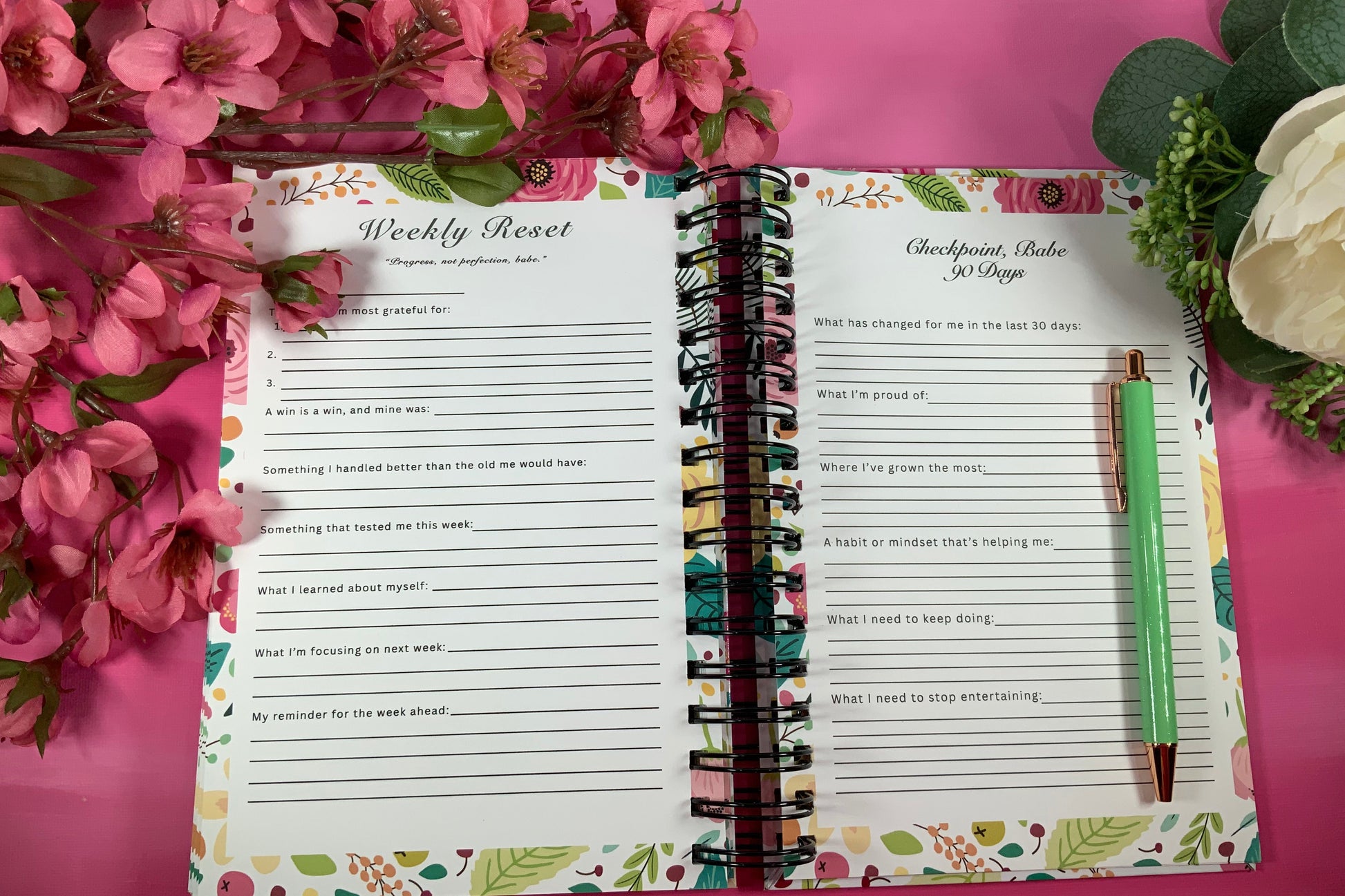 Open planner with weekly反省页面 on a pink background with flowers