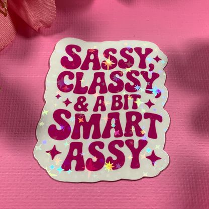 Sticker with 'Sassy Classy & A Bit Smart Assy' text on a pink background with flowers and pearls.