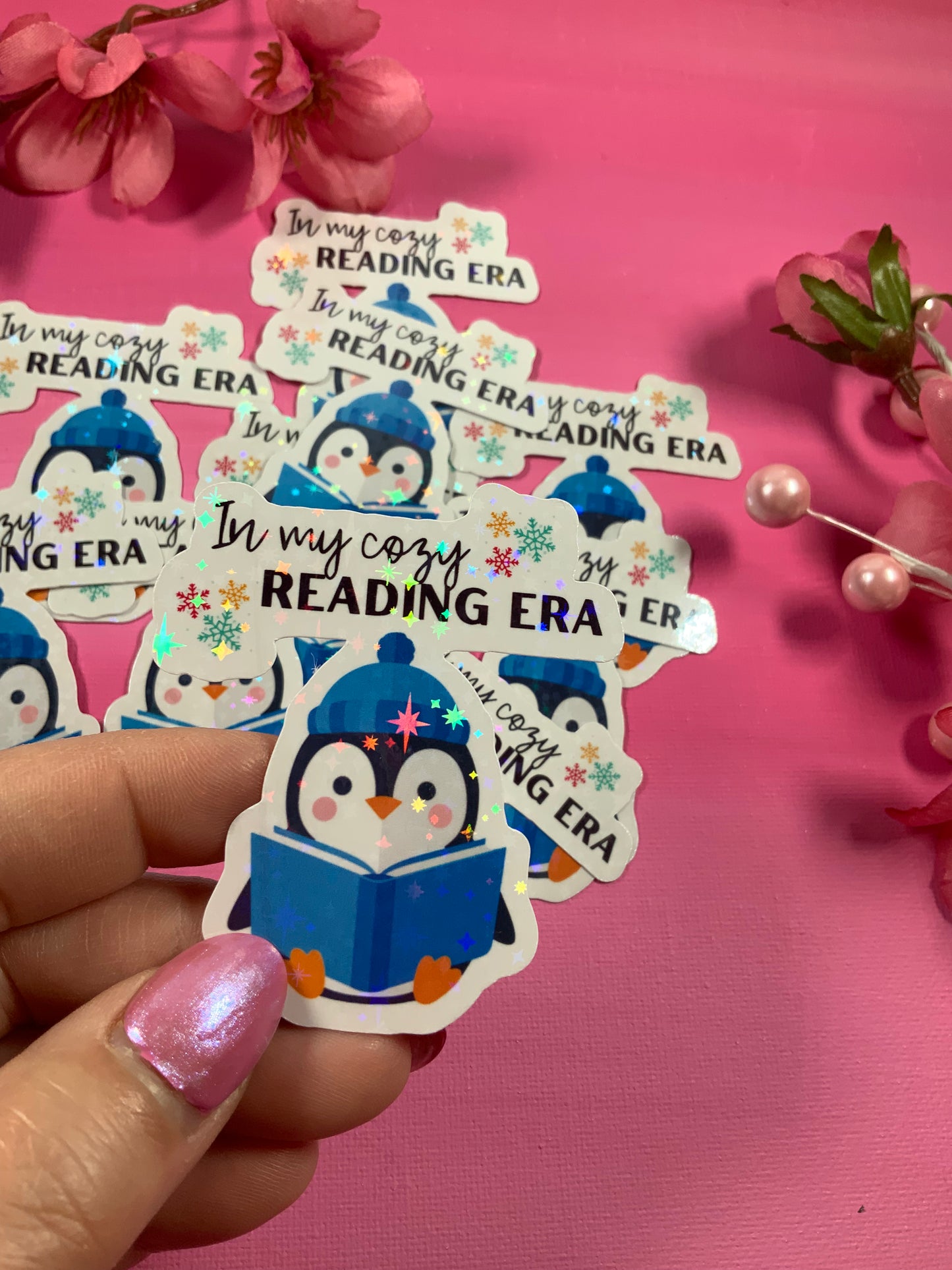 Sticker with a penguin reading a book and 'In my cozy READING ERA' text on a pink background.