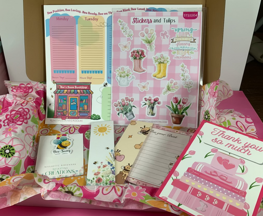 Collection of stationery items including notebooks and cards on a pink surface.