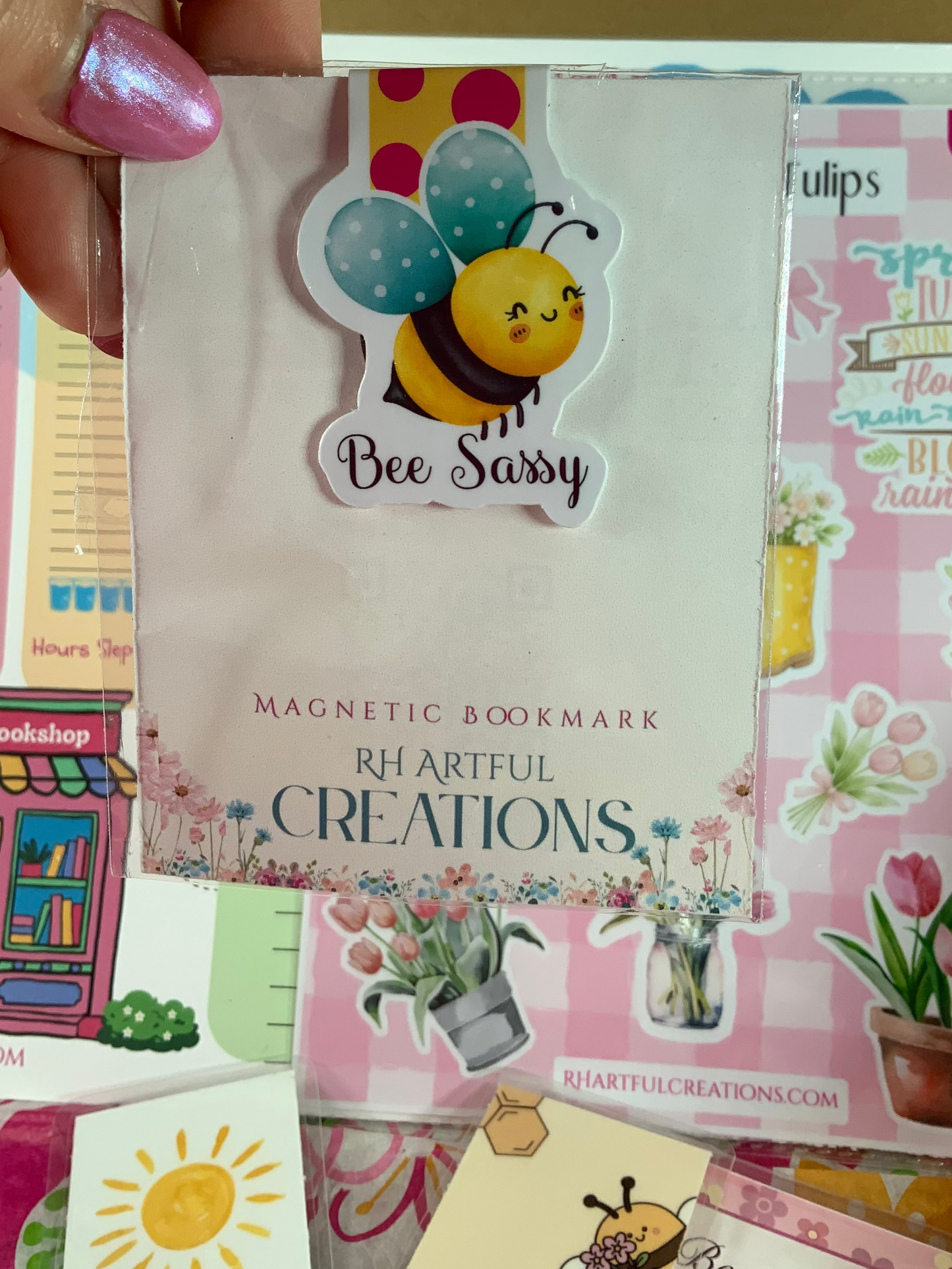Magnetic bookmark with bee design held by a hand against a colorful background