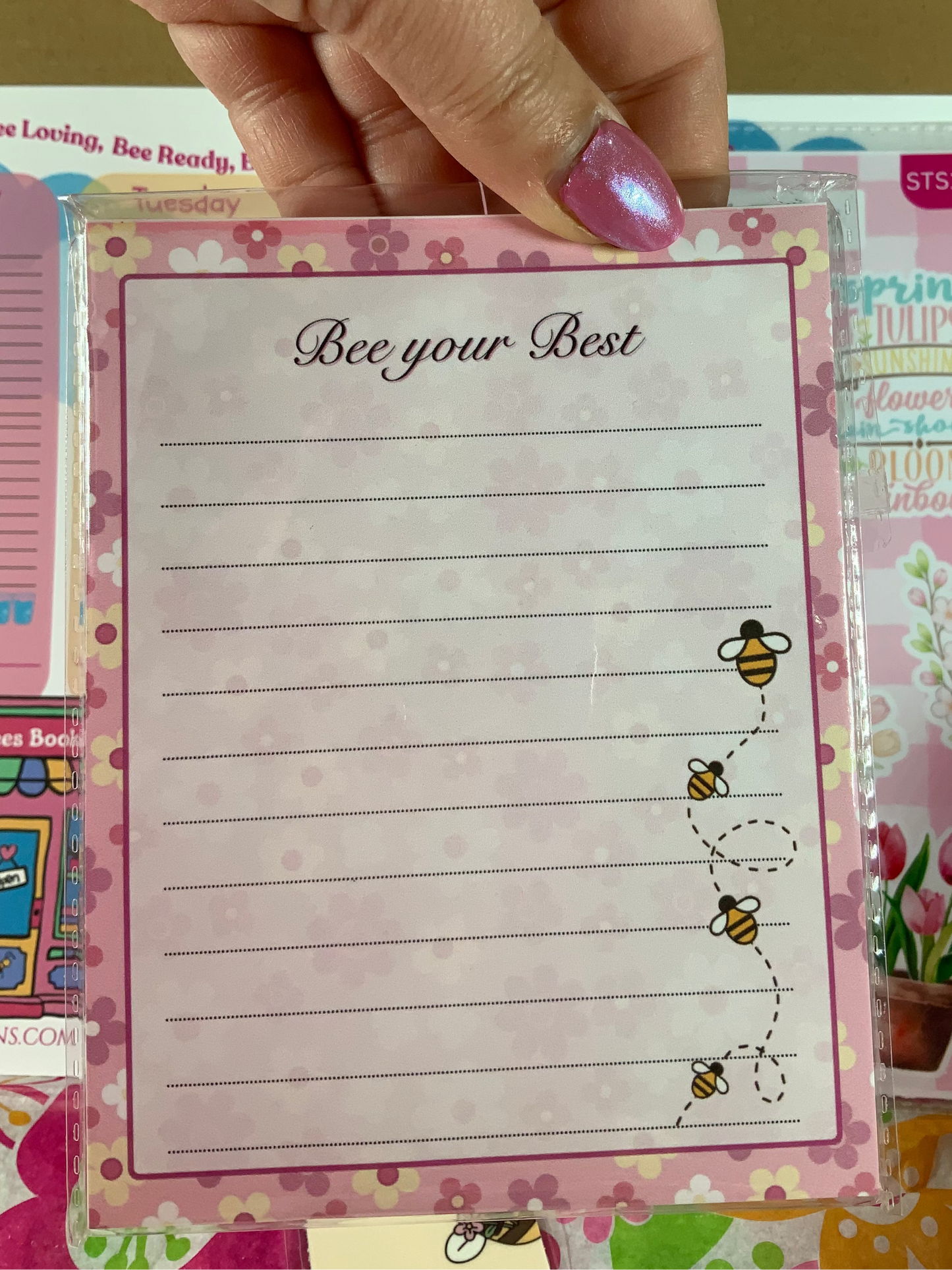 Notebook with 'Bee your Best' text and bee illustrations held by a hand.