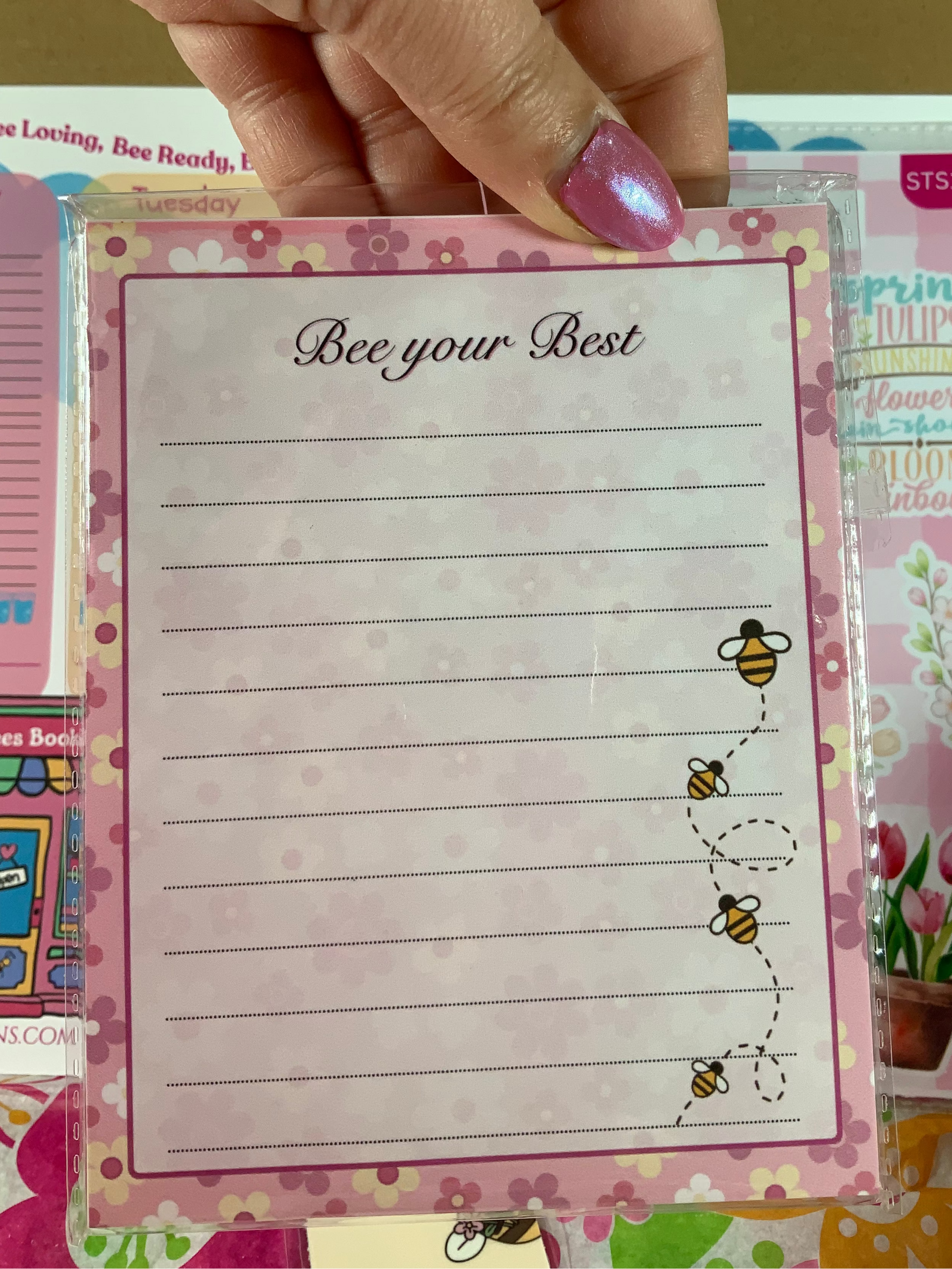 Notebook with 'Bee your Best' text and bee illustrations held by a hand.