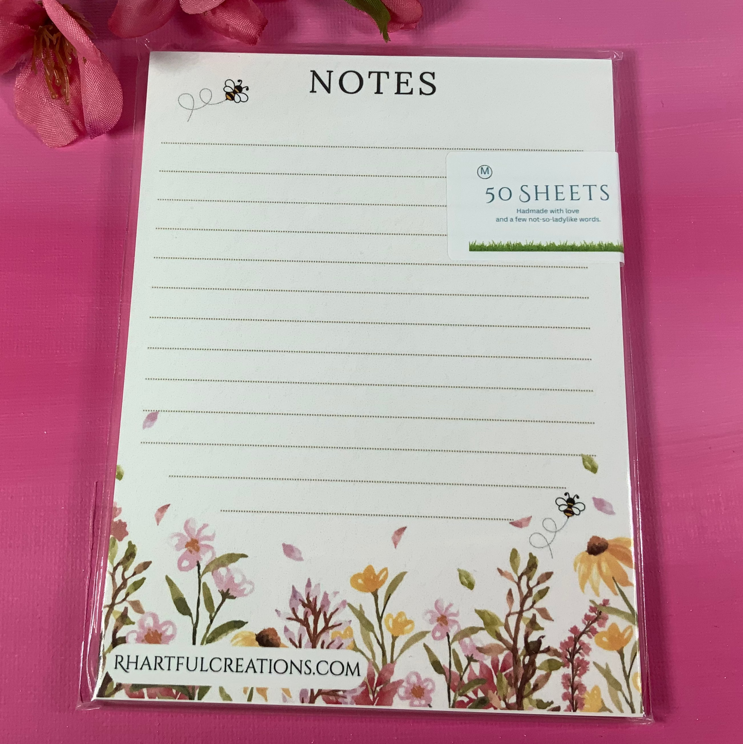 Floral notepad with decorative border on a pink background