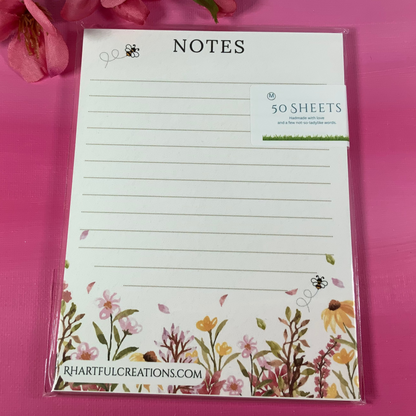 Floral notepad with decorative border on a pink background