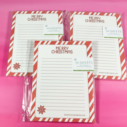 Set of Christmas-themed notepads with candy cane design on a pink background