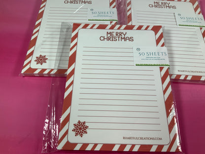 Set of Christmas-themed notepads with red and white striped borders on a pink background.
