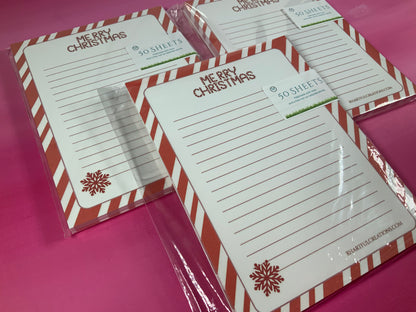 Merry Christmas-themed notepads with red and white striped borders on a pink background