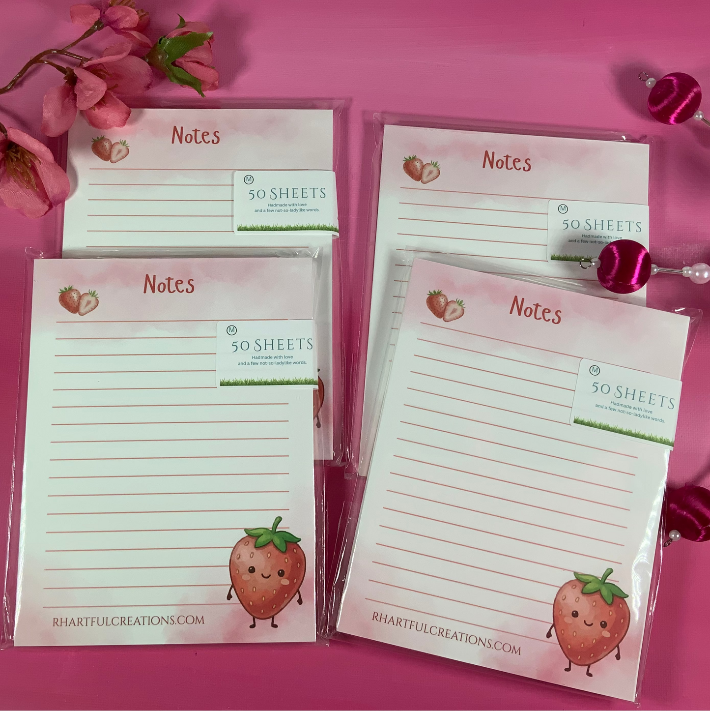 Set of strawberry-themed notepads on a pink background with decorative elements.