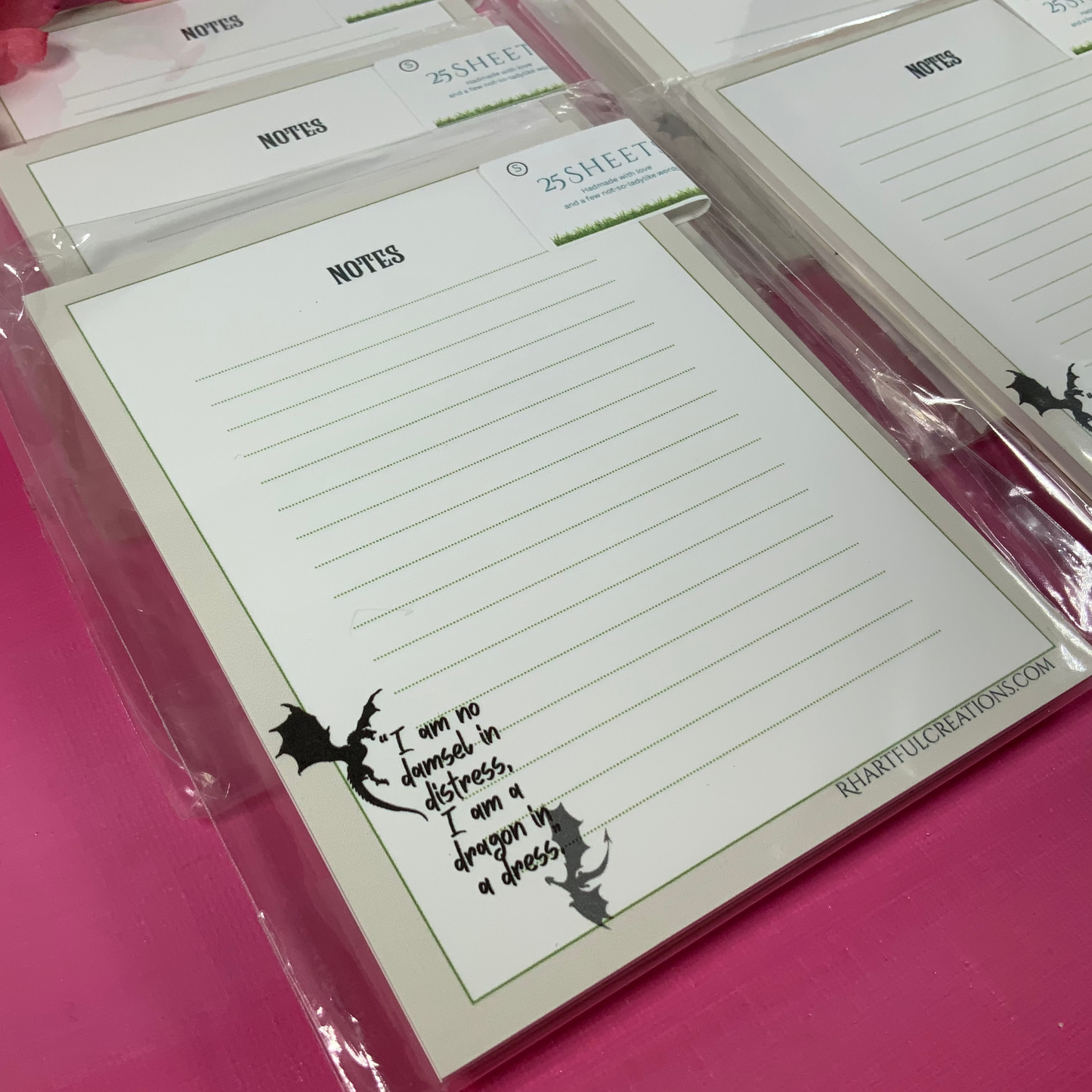 Note pads with writing surface and decorative text on a pink background