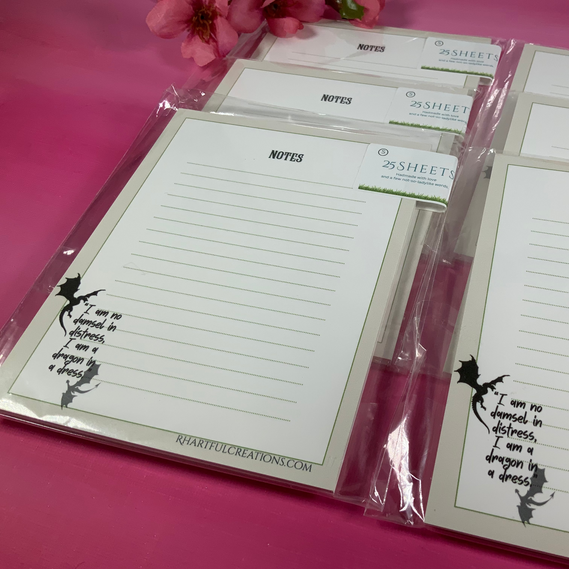 Note pads with writing prompts on a pink surface