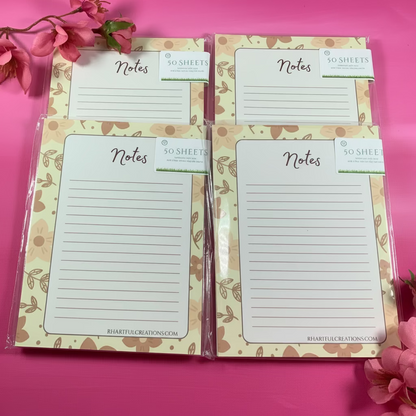 Two floral-patterned note pads with 'Notes' text on a pink surface with flowers.