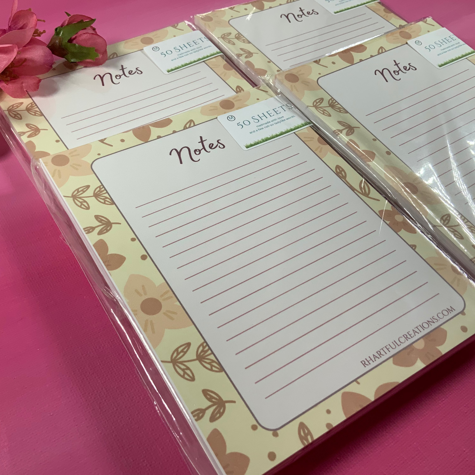 Set of floral notepads with 'Notes' text on a pink surface.