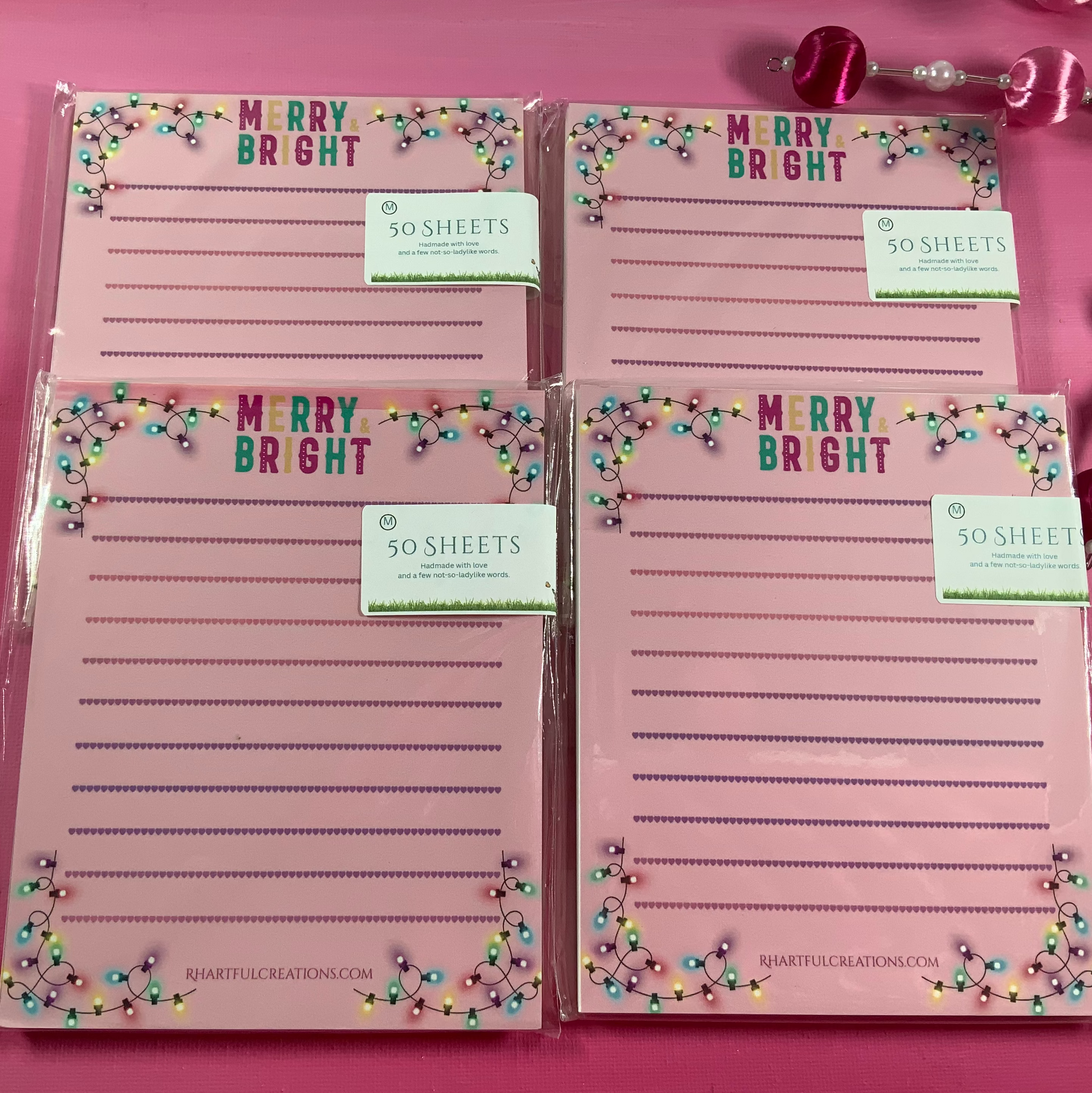 Set of four pink notepads with 'Merry Bright' text on a pink background